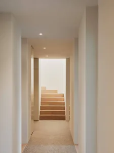 A modern minimalist interior with wooden stairs and white walls.