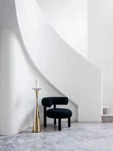 A minimalist staircase with a black upholstered chair on a marble floor.