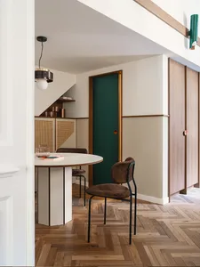 Modern dining room with wooden flooring, green door, and minimalist furniture.