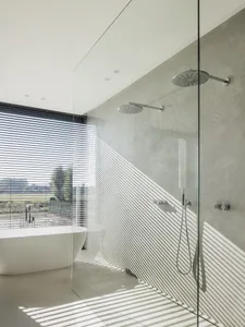 A modern minimalist bathroom with concrete walls, glass shower enclosure, and a freestanding bathtub.
