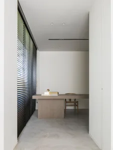 A minimalist home office with concrete flooring, a wooden desk, and a chair.