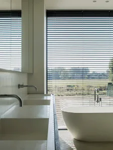 Modern bathroom with white concrete walls and floor, featuring a minimalist bathtub and sleek, contemporary fixtures.