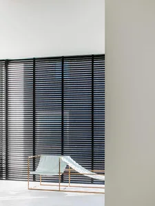 Modern interior featuring metallic blinds, minimalist furniture, and geometric shapes.