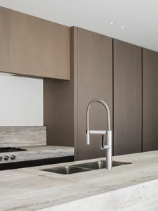 A modern kitchen with a stone countertop and a waterfall edge sink.