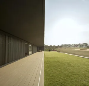 Modern building with wooden deck overlooking a golf course.