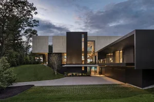 A modern house featuring a concrete exterior with large windows and a sleek design.