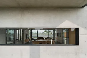 Modern living room featuring a concrete wall with a large window.