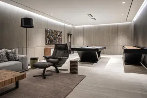 Modern living room featuring a contemporary leather recliner chair, wooden coffee table, and a sleek black pool table with bi