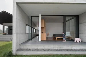 Modern minimalist bedroom with concrete walls, wooden furniture, and glass windows.