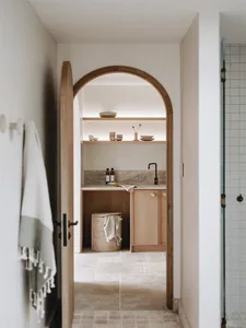 A modern minimalist kitchen with wooden cabinets and stone countertops.