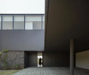 A modern residential exterior featuring metal-clad siding and a concrete floor.