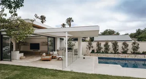 A modern minimalist residential space featuring concrete, glass, and wooden elements.