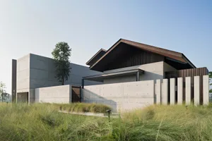 Large modern residential building with concrete exterior and greenery surrounding it.