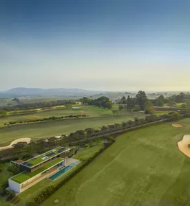 Modern residential home with a green roof and rooftop garden overlooking a golf course and countryside.