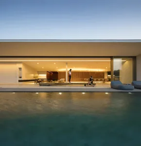 A modern residential poolside area with concrete walls and large glass doors.