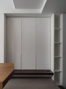 A minimalist bedroom featuring white cabinets and wooden furniture.