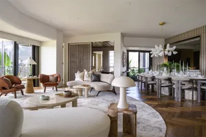 A modern interior design featuring living and dining areas with a mix of wood texture, concrete, marble, leather, and fabric 