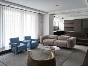 Contemporary living room with blue armchairs, gray sofa, and marble coffee table.