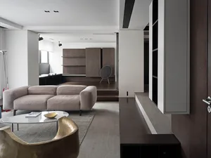A modern living room with a beige sofa, a round coffee table, and a round speaker on a wooden shelf.
