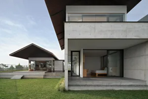 A modern residential exterior with a concrete exterior and large windows.