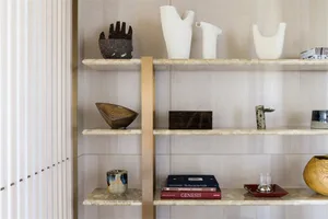 Modern shelf decorated with marble vases and books on a white wall background.