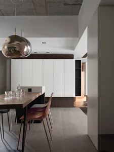 A minimalist living room with a concrete floor, exposed ceiling beams, and contemporary furniture.