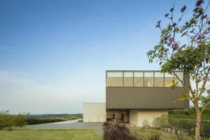 Modern residential house with glass cladding and large windows.