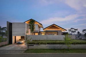 A modern residential home with a concrete exterior and minimalist design, illuminated by warm lights.