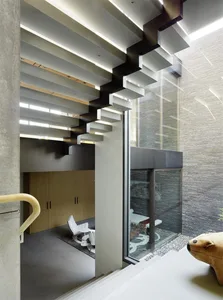 A modern staircase with exposed concrete beams and a glass wall.