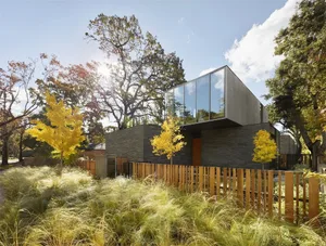 A minimalist modern residential exterior with glass walls and stone materials.