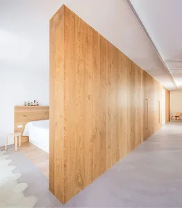 Spacious bedroom with white walls, natural wooden flooring, and a large wooden partition.