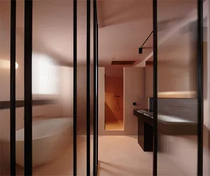 A minimalist bathroom with a glass partition, white bathtub, and black accents.