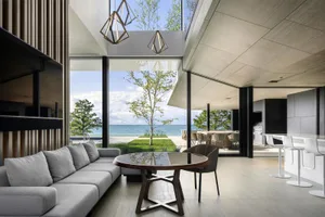 Modern living room featuring a large sectional sofa, round glass table, and geometric lighting fixtures.