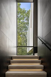 Modern staircase with light-up steps leading to a view of a forest.