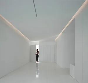 Minimalist interior space with white walls, floor, and lighting fixtures.