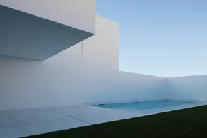 A minimalist poolside area featuring concrete walls and glass railings.