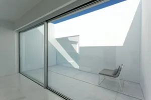 A minimalist balcony featuring glass walls, concrete floor, and metal accents.