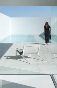 A minimalist patio with a white chair and concrete floor.