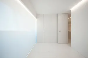 Empty white minimalist room with closed doors and sleek lines.