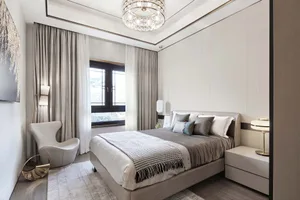 A modern bedroom featuring gray and taupe colors with a bed, nightstands, and a contemporary armchair.