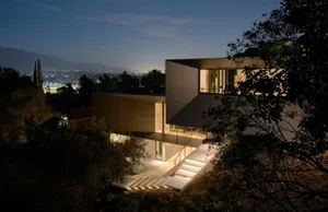 Modern residential house with concrete exterior illuminated at night.