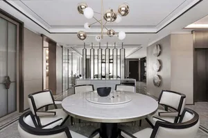 Modern living room with white marble accents, featuring sleek, black and white furniture and a contemporary light fixture.