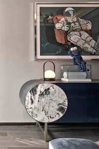 Modern living room with marble coffee table and metallic accents, featuring an astronaut-themed artwork on the wall.