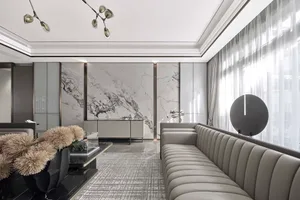 Modern living room with marble walls, glass furniture, and a contemporary chandelier.