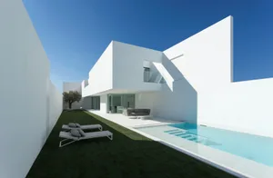 Modern minimalist house with white exterior, glass walls, and swimming pool.