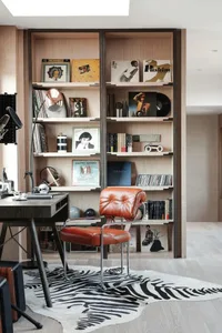 A modern office space with wooden walls, a leather chair, and a zebra print rug.
