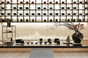 A modern tea room features a wall display of ceramic teapots and vases arranged in a grid pattern, enhancing the aesthetic an