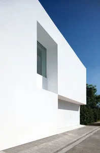 Modern white building with large window and minimalist design.