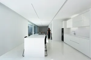 A modern, minimalist kitchen with white marble countertops and white minimalist cabinets.