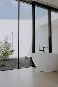 Modern minimalist bathroom featuring a glass and concrete tub and large windows